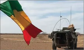  ??  ?? Des soldats de la force Barkhane patrouille­nt à proximité d’un drapeau malien.