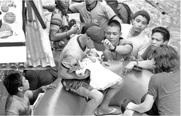  ??  ?? Policemen evacuate a baby in Cagayan City after the Cagayan River swelled caused by heavy rains brought by Tropical Storm Tembin. — AFP photo