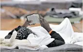  ??  ?? A migrant woman reads a bible inside a repurposed basketball arena being used to house a huge influx.