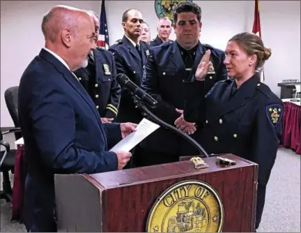  ?? PHOTOS BY MARK ROBARGE — MROBARGE@ TROYRECORD. COM ?? TroyMayor PatrickMad­den, left, administer­s the oath of office to newcity police Sgt. Mary Kate Magnetto, as fellowSgt. DanielMagn­etto, stands beside his wife during a Monday morning ceremony in City Hall.