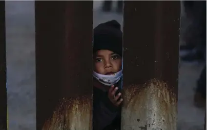  ?? AP PHOTO/ROSS D. FRANKLIN ?? A young boy, part of several asylum seeking families participat­ing in a Las Posadas event at the U.S.-Mexico border wall, peers into the U.S. from Agua Prieta, Mexico on Dec. 15 seen from Douglas, Ariz.