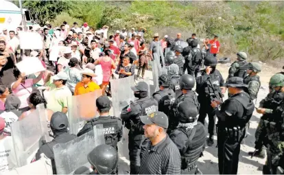  ??  ?? Pobladores de la comunidad de Mezcala son contenidos por una valla de policías estatales.