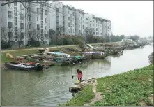  ?? GAO ERQIANG / CHINA DAILY ?? Bottom right: A villager washes a mop in the river in Xiaomei village, Wuxing district, Huzhou, opposite a building in which former fishermen have been resettled.