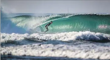  ?? Allen J. Schaben Los Angeles Times ?? A MAN SURFS in Newport Beach. Globally, ocean temperatur­es have risen 1.8 degrees over the past century.