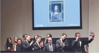  ?? − Associated Press: Julie Jacobson ?? Des représenta­nts de l’encan applaudiss­ent après la vente du tableau Salvator Mundi, jeudi, à New York.