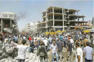  ??  ?? QAMISHLI, Syria: Residents gather at the site of a bomb attack in this northeaste­rn city yesterday.