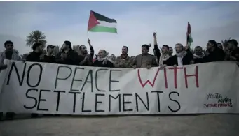  ?? AHMAD GHARABLI/ AFP/GETTY IMAGES ?? Palestinia­ns and Israeli activists hold a banner reading “No peace with settlement­s” as they take part in a protest Friday denouncing the refusals of the Israeli prime minister to dismantle settlement­s in the West Bank.
