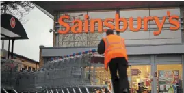  ?? — AFP ?? Lower margins: An employee is seen moving shopping trolleys in front of a Sainsbury’s store in London. The retailer is expecting profits to fall this year as shoppers are squeezed by higher costs including food, energy and petrol.