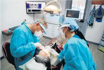  ?? SUSAN STOCKER/SOUTH FLORIDA SUN SENTINEL ?? Dr. Darren Snow and his assistant, Crissie Ramirez, of Emerald Hills Dental in Hollywood, work on patient Rosa Kavanagh on May 11.