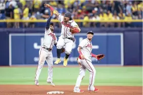  ?? (AP Photo/mike Carlson) ?? Atlanta Braves’ Ronald Acuna Jr., center, celebrates with Ozzie Albies, left, and Orlando Arcia Friday after the team’s 2-1 win over the Tampa Bay Rays in a baseball game in St. Petersburg, Fla.