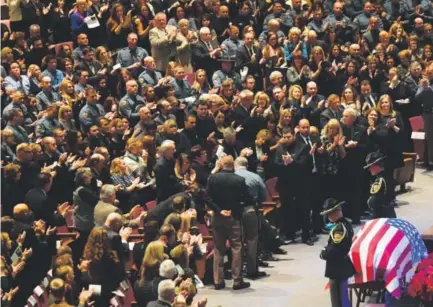  ??  ?? Mourners stand and applaud the family of Colorado State Patrol Trooper Cody Donahue during his funeral Friday at Denver First Church of the Nazarene. Donahue was killed Nov. 25 on Interstate 25 during an accident investigat­ion. RJ Sangosti, The Denver...