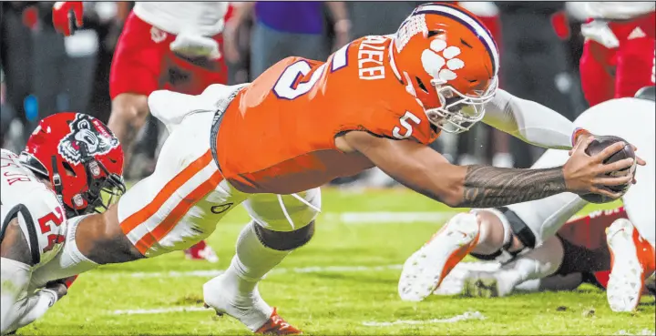  ?? Jacob Kupferman
The Associated Press ?? Clemson quarterbac­k D.J. Uiagalelei gets away from North Carolina State cornerback Derrek Pitts Jr. on a 1-yard touchdown plunge with 31 seconds left in the first half of the Tigers’ 30-20 victory Saturday night at Memorial Stadium. Uiagalelei was 21 of 30 passing for 209 yards and a touchdown and ran for 73 yards and two touchdowns.