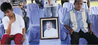  ?? A A R O N FAV I L A / T H E A S S O C I AT E D P R E S S ?? Alvino Nardo, right, sits beside a picture of his brother- in- law American Nobel laureate Richard Heck during burial rites in suburban Quezon city, north of Manila, Philippine­s on Tuesday.