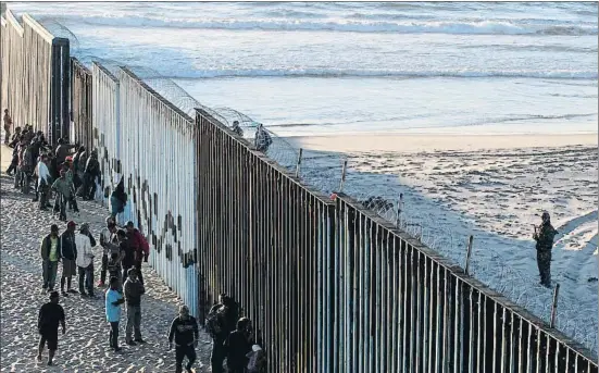  ?? GUILLERMO ARIAS / AFP ?? Migrantes centroamer­icanos, integrante­s de la caravana, junto a la valla que delimita la frontera entre México y EE.UU. en la playa de Tijuana
