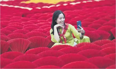  ?? Pictures: AFP ?? INSTAGRAM-WORTHY. A tourist takes a selfie in front of incense sticks arranged by families living and working in Quang Phu Cau.