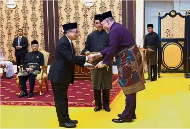  ?? — Bernama ?? It’s official: Yang di-Pertuan Agong Sultan Muhammad V presenting the letter of appointmen­t to Malanjum at Istana Negara. Looking on is Prime Minister Tun Dr Mahathir Mohamad.