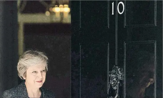  ?? DANIEL LEAL-OLIVAS / AFP ?? Theresa May, ayer saliendo a la puerta de su residencia oficial en el 10 de Downing Street para recibir a una comitiva de Qatar