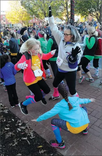  ?? NWA Democrat-Gazette/FLIP PUTTHOFF ?? Girls dance to warm up and stretch in November before taking part in the Girls on the Run 5K run in downtown Bentonvill­e. Girls on the Run is a national program that encourages pre-teen girls to develop self-respect and healthy lifestyles through class...