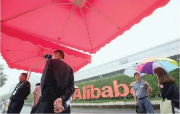  ?? — Reuters ?? People stand near a sign of Alibaba Group at its campus in Hangzhou, Zhejiang Province, China.