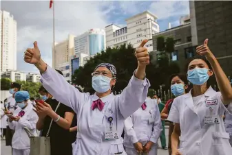  ?? Chinatopix ?? Medical workers in Fuzhou, China, cheer their colleagues who departed to help contain an outbreak of COVID-19 in the city of Putian in Fujian province south of Shanghai.