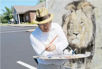  ??  ?? Mark Balma pinta un mural de “Cecil” cerca de la vivienda del dentista Walter Palmer.