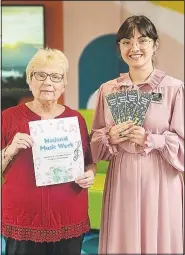  ?? (Courtesy Photo/Cynthia Augspurger) ?? Andante member Cynthia Augspurger displays a coloring page promoting National Music Week while Ashdon Wilson, Youth Services Librarian at Bella Vista Public Library, holds bookmarks with the NMW logo.