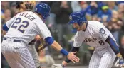  ?? ASSOCIATED PRESS ?? Christian Yelich (22) and Ryan Braun celebrate Braun’s two-run home run.