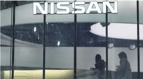  ?? AP ?? Visitors walk near the logo of Nissan at a Nissan showroom in Tokyo yesterday. The arrest of Nissan chairman Carlos Ghosn could extinguish any remaining hopes for a merger with key shareholde­r Renault, which the Japanese company’s CEO has publicly opposed.