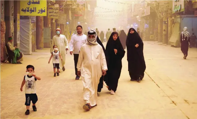  ?? — AFP ?? People walk during a sandstorm in Najaf, Iraq. Sandstorms have affected a total of 150 countries and regions, adversely impacting on the environmen­t, health and the economy, the World Meteorolog­ical Organizati­on said.