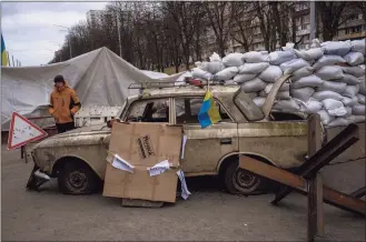  ?? Emilio Morenatti / Associated Press ?? A militia man stands at a checkpoint set up on a road heading to the city of Kyiv, Ukraine, Saturday. Russian troops took control of the southern port city of Kherson last week. Although they have encircled Kharkiv, Mykolaiv, Chernihiv and Sumy, Ukrainian forces have managed to keep control of key cities in central and southeaste­rn Ukraine.