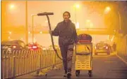  ?? AP ?? Chinese artist Wang Renzheng demonstrat­es the use of his industrial shop-vac alongside a highway in Beijing on Tuesday. Wang spent four hours a day for 100 days vacuuming the Beijing air with an industrial shop-vac, then baked the accumulate­d dust into...