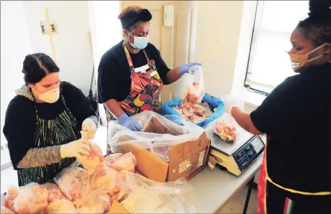  ?? Christian Abraham / Hearst Connecticu­t Media ?? PT Partner organizer Dione Dwyer, center, bags up chicken to give out to residents at the monthly PT Barnum food distributi­on event in Bridgeport on April 4, 2020. Helping Dione at right is Shaurice Bacon, one of many lower-income state residents who feel trapped by Connecticu­t’s lack of affordable housing.