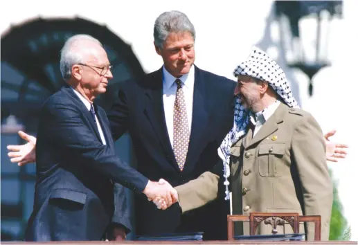  ?? (Gary Hershorn/Reuters) ?? PLO CHAIRMAN Yasser Arafat shake hands with prime minister Yitzhak Rabin, as US president Bill Clinton stands between them, after the signing of the Israeli-PLO peace accord, at the White House, September 13, 1993.