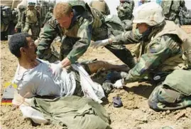  ?? LAURENT REBOURS/AP 2003 ?? U.S. Navy medics treat an Iraqi POW. Recent wars have had a profound impact on the national debt, now six times what it was at the start of the 21st century.