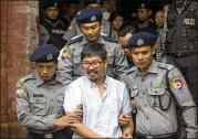  ?? THEIN ZAW / AP ?? Reuters journalist Wa Lone is escorted by police Monday as he leaves the court after a ruling that he and another reporter will face trial in Myanmar.