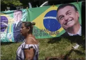  ?? SILVIA IZQUIERDO — THE ASSOCIATED PRESS ?? A woman walks past a banner Saturday featuring the Brazilian national flag and an image of former President Jair Bolsonaro in Rio de Janeiro, Brazil. The message, in Portuguese, reads “Ex, most beloved of Brazil.”