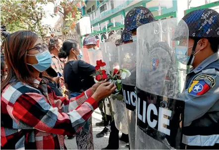  ?? AP ?? Protesters offer roses to riot police as four arrested activists appear in court in Mandalay yesterday. Students and teachers have taken to the streets throughout Myanmar to demand that the military hand power back to elected politician­s, as resistance to last weekend’s coup grows.