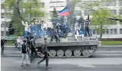  ?? Picture: REUTERS ?? STREET FIGHTERS: People ride on a towed tank abandoned after Ukrainian forces attacked pro-Russian militants in the southeaste­rn port city of Mariupol