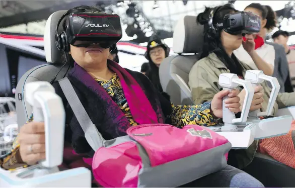  ??  ?? Visitors try out virtual reality headsets at the Beijing Auto Show, the premier annual event for carmakers to present their latest models in China. Letting customers manipulate models, colour schemes and features in a virtual environmen­t is automakers’...