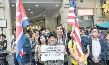  ?? — AFP ?? US President Donald Trump and North Korea’s leader Kim Jong Un sit for a dinner at the Sofitel Legend Metropole Hotel in Hanoi. Right: A crowd of onlookers wait outside the hotel as Trump and Kim Jong Un meet for dinner.