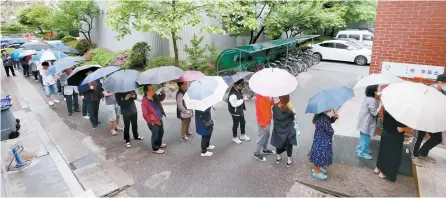  ?? Yonhap ?? Voters wait in the rain outside a polling station in Nowon-gu, northeaste­rn Seoul, Tuesday, to cast their ballots for the presidenti­al election.