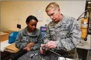  ?? AIR FORCE PHOTO U.S. ?? Tech. Sgt. Brandon Dutreix, 403rd Operations Support Squadron aircrew flight equipment craftsman, instructs Senior Airman Tabitha Williams, 403rd OSS aircrew flight equipment journeyman, on how to assemble and inspect an AN/URT-44 personnel locator beacon Jan. 10, 2015. The Air Force Life Cycle Management Center’s Agile Combat Support Directorat­e is currently fielding 12,000 new personnel locator beacons to replace the URT-44.