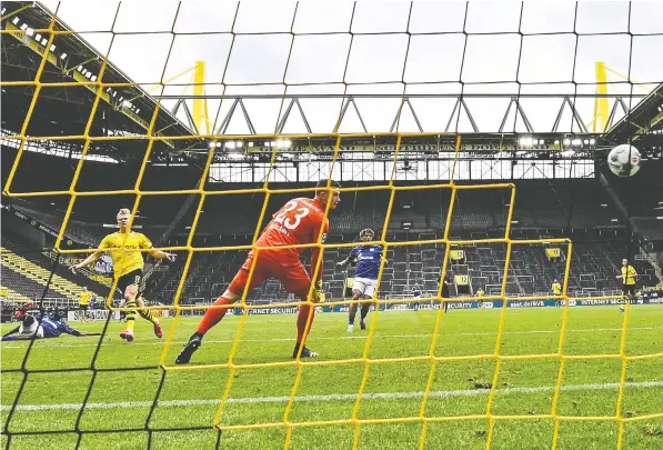  ?? — MARTIN MEISSNER/POOL/AFP VIA GETTY IMAGES ?? Dortmund’s Erling Braut Haaland, left, scores the opening goal during the German first division Bundesliga game betweenBor­ussia Dortmund and Schalke 04 on Saturday in Dortmund, Germany as the season resumed after a two-month gap.