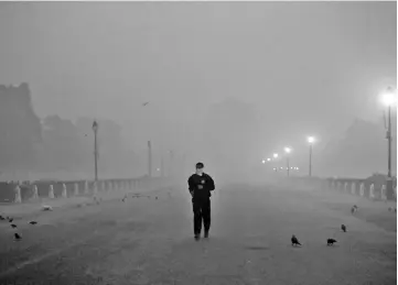  ??  ?? A man with his face covered walks in front of the India Gate amidst smog in the early morning in New Delhi, India. — Reuters photo