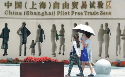  ?? WU JUN/FOR CHINA DAILY ?? Two pedestrian­s walk past the Shanghai FTZ.