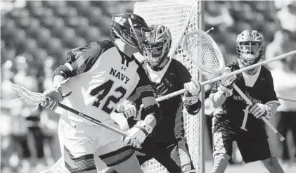  ?? PAUL W. GILLESPIE/BALTIMORE SUN MEDIA GROUP ?? Navy's Jack Ray, left, works his way around Holy Cross' Matt Farrell in the first quarter. Ray, Navy’s top scorer, was held without a goal.