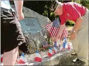  ?? DANA JENSEN/THE DAY ?? John Waggoner, president of the Norwich Area Veterans Council, and a fellow member place French flags at a memorial during a ceremony Tuesday for the 20 French sailors who died in 1778 and are buried at the historic Norwichtow­n burial ground. The sailors from France, America’s ally during the American Revolution­ary War, were prisoners of the British at the time. The event was hosted by the Norwich Area Veterans Council.