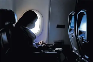  ?? AP PHOTO/CHARLIE RIEDEL ?? A passenger wears a face mask she travels on a Delta Airlines flight Wednesday after taking off from Hartsfield-Jackson Internatio­nal Airport in Atlanta. Amid fears of new variants of the virus, new restrictio­ns on movement have hit just as people start to look ahead to what is usually a busy time of year for travel.