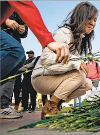  ?? ?? A WOMAN and a girl place f lowers at a memorial Sunday for victims of the mass shooting Saturday night at a ballroom
dance studio. Monterey Park canceled the second day of its Lunar New Year festival on Sunday because of the attack.