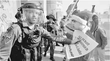  ??  ?? A Palestinia­n dressed as Santa Claus argues with an Israeli border police during clashes in the West Bank city of Bethlehem. — Reuters photo